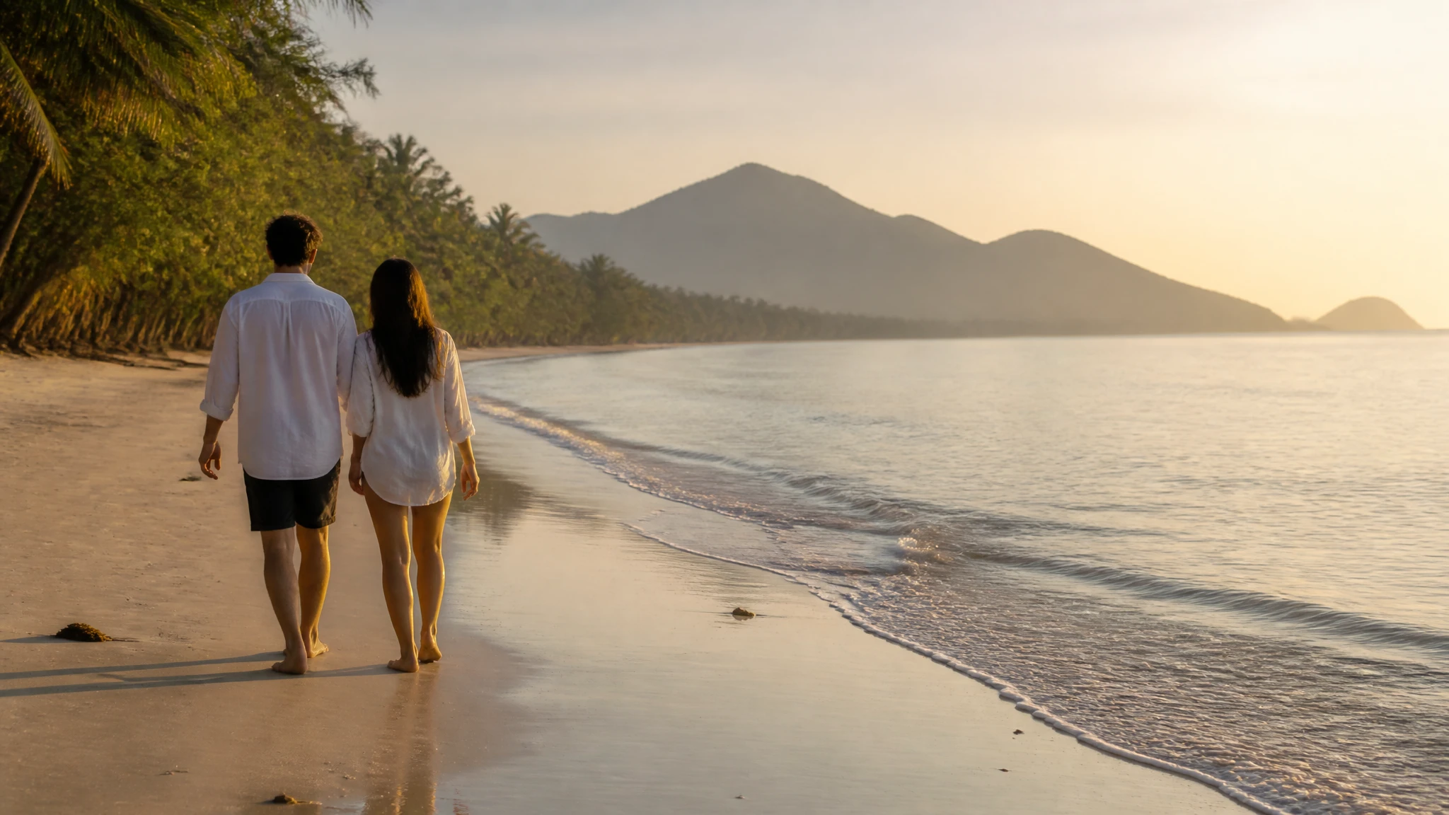 Couple walking along a quiet Thai beach during the off-season with golden light and calm waters